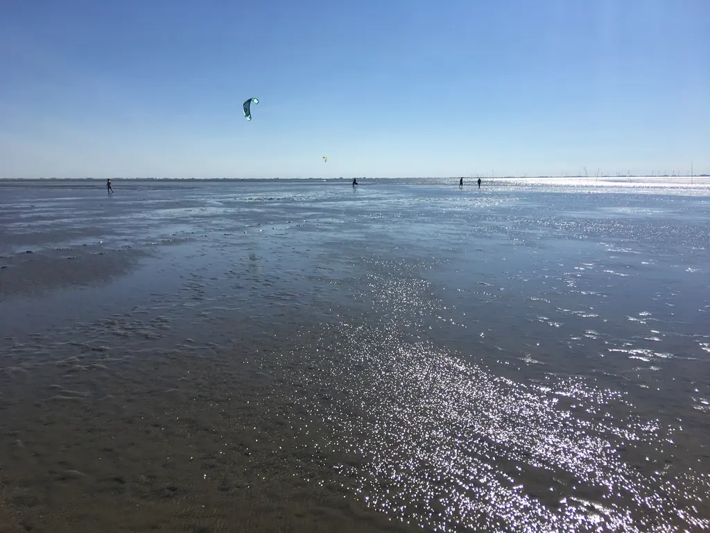 Weites Watt mit Kitesurfer am Horizont