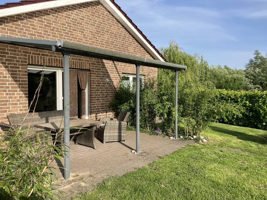 Terrasse mit Überdachung und Blick in den eingezäunten Garten