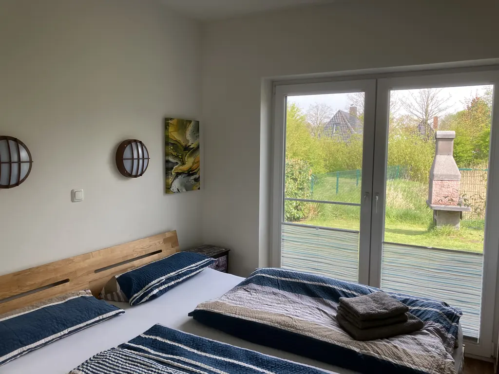 Schlafzimmer mit großem Bett und Fenstertür zum Garten