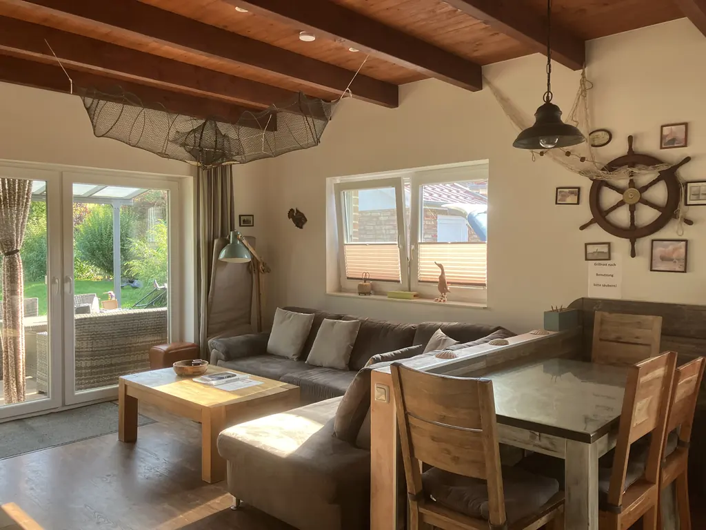 Wohn- und Essbereich mit Sofa, Esstisch und Steuerrad an der Wand